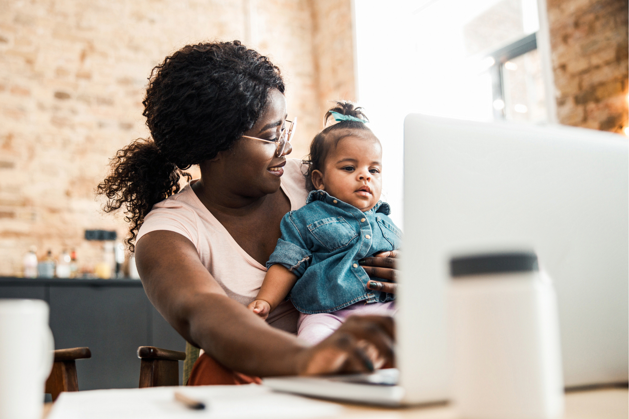 Image of a mother with her baby sitting in front of a laptop reading from the computer