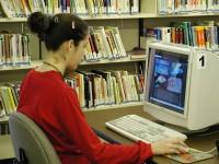 Woman sitting infront of an old computer inside a library