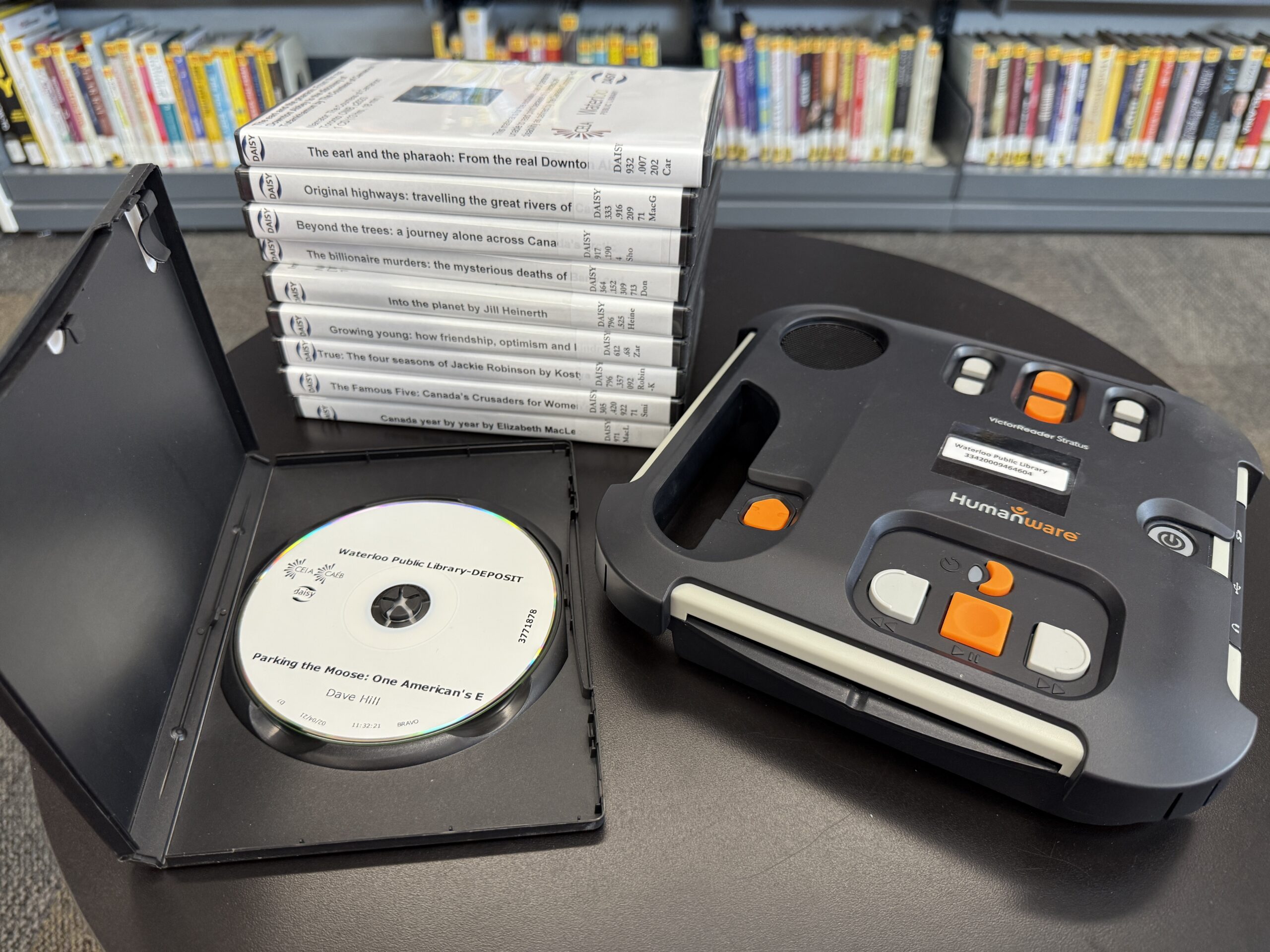 Daisy Player and 10 CD-based audiobooks sitting on a table at the library.
